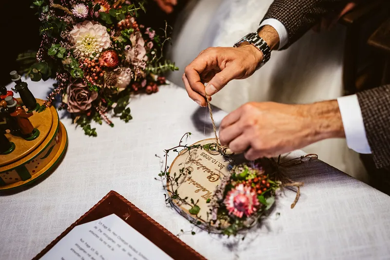 Hände ordnen etwas auf dem Hochzeitstisch