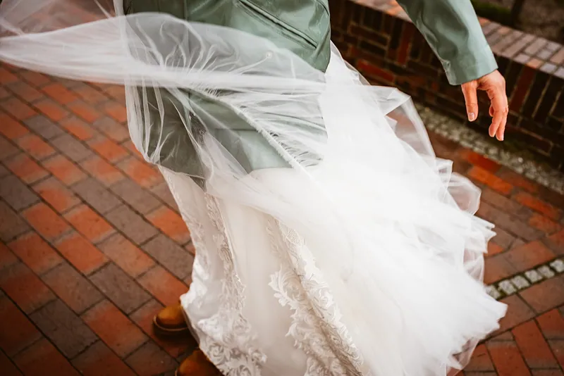 Das Brautkleid weht über dem nassen Pflaster