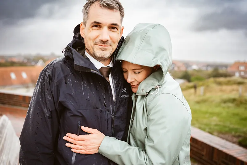 Mel und Christoph in Regenjacken vor der Inselkulisse