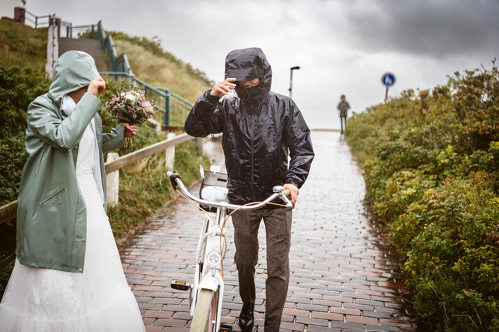 Mel und Christoph mit Regenjacken und Fahrrädern auf Langeoog