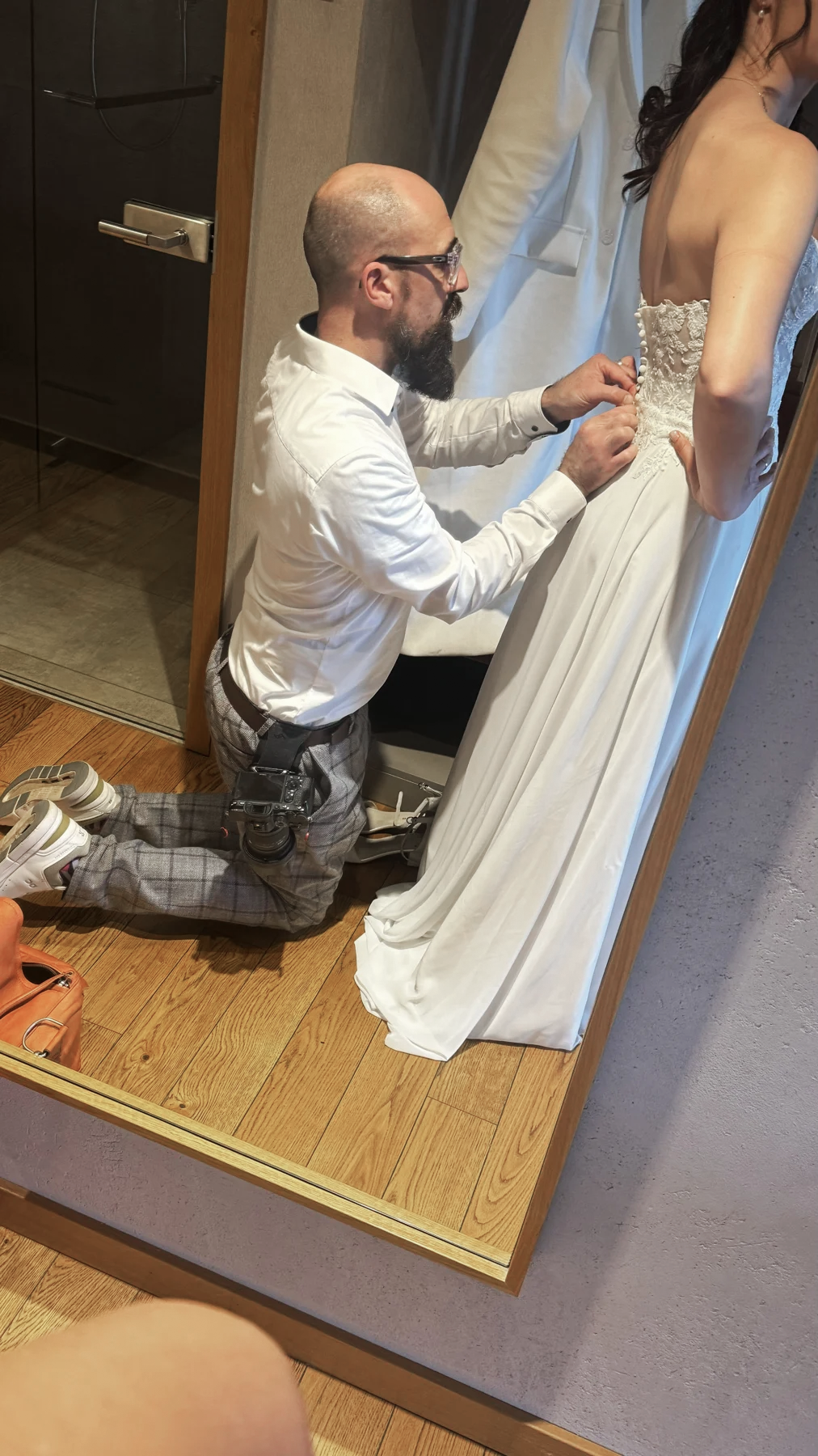 Marc hilft Michelle beim Schließen der Knöpfe ihres Brautkleids