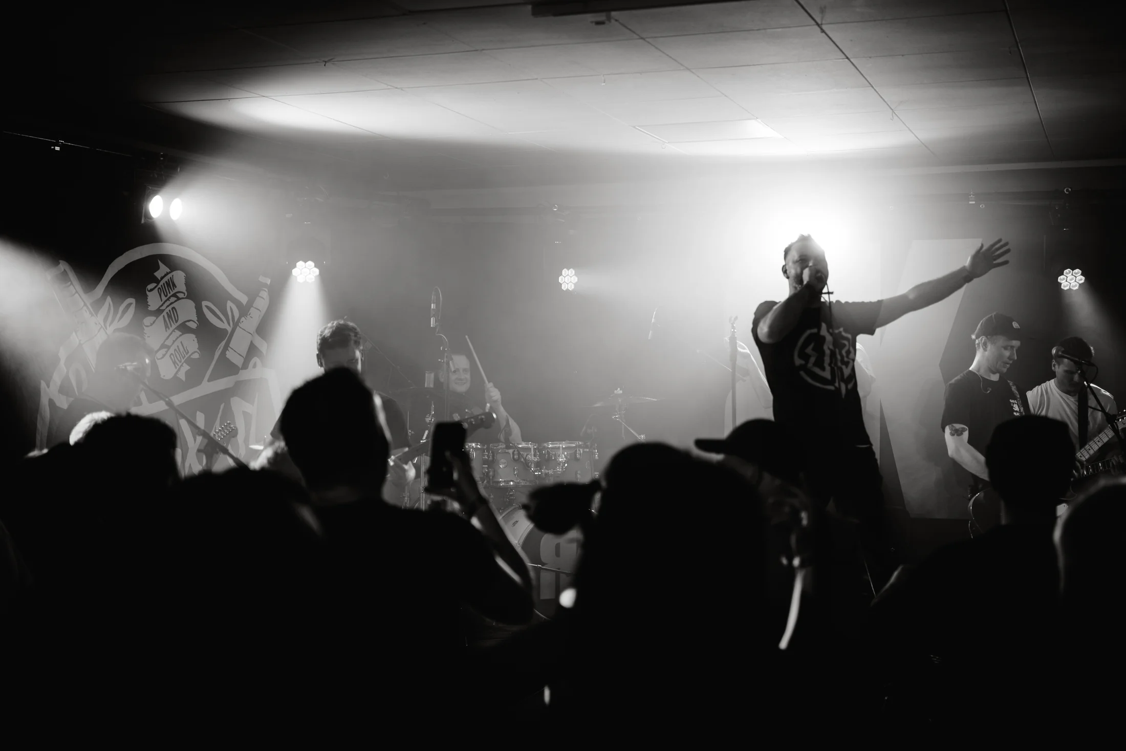 Konzertmoment in Schwarzweiß, Band auf der Bühne und Publikum davor