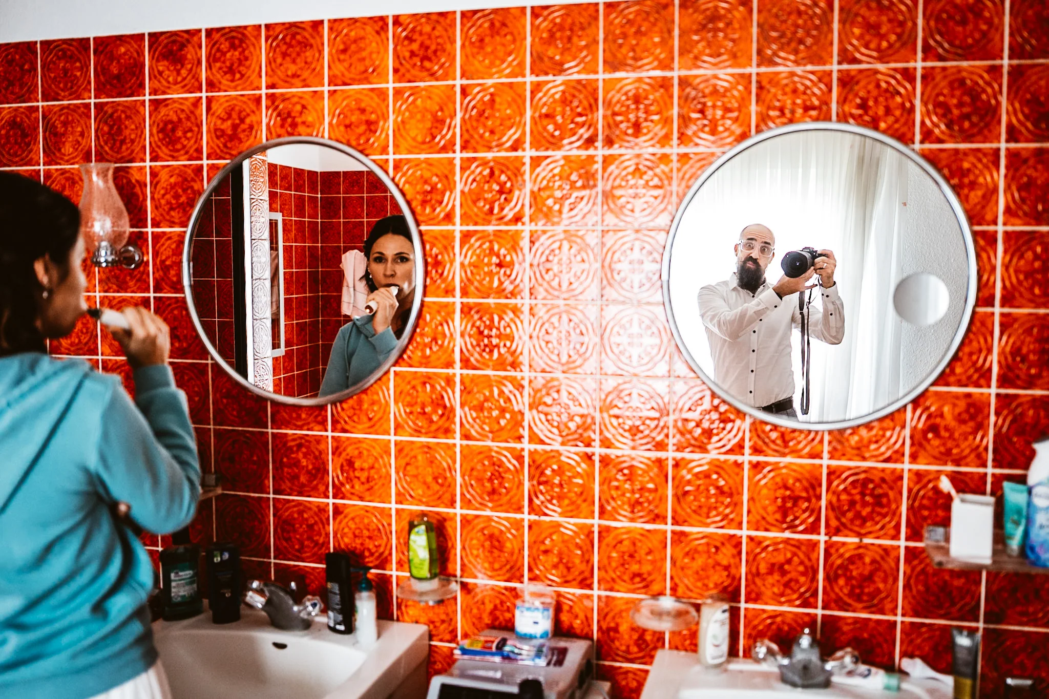 Braut putzt beim Getting Ready die Zähne, während Marc im zweiten Spiegel fotografiert