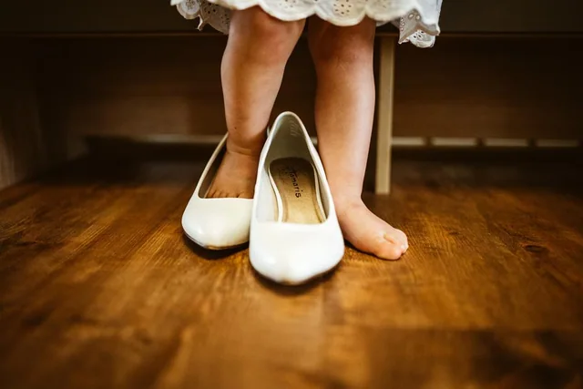 Kleine Füße neben den Brautschuhen der Mutter
