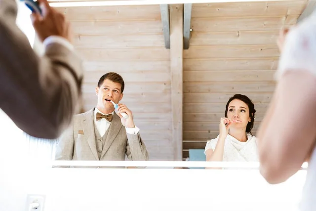 Braut und Bräutigam putzen beim Getting Ready gemeinsam Zähne vor dem Spiegel