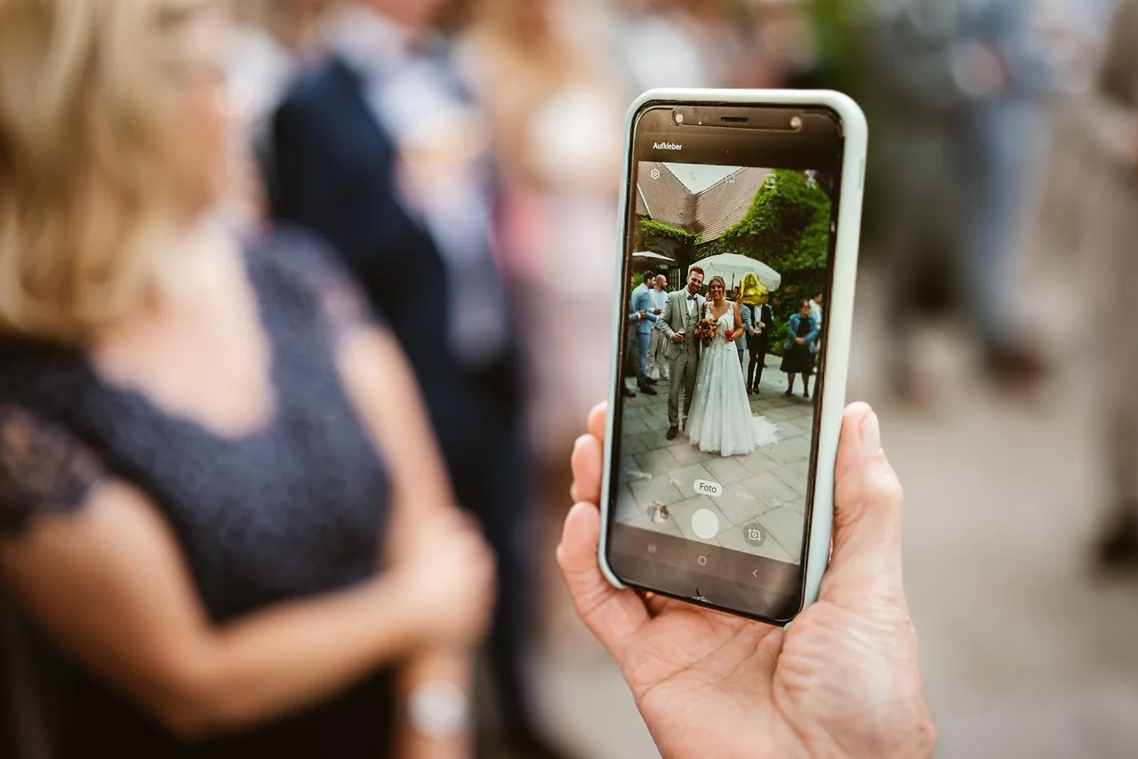 Auf dem Handy der Oma ist ihr Foto des Brautpaares zu sehen