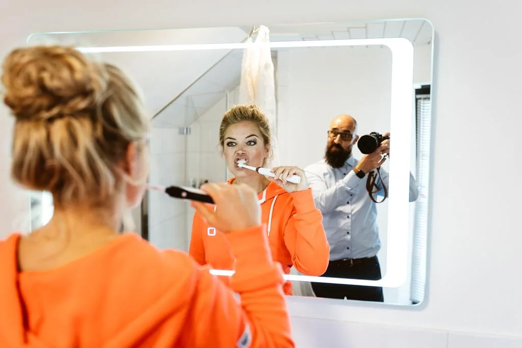 Braut putzt die Zähne und Marc fotografiert im Spiegel mit