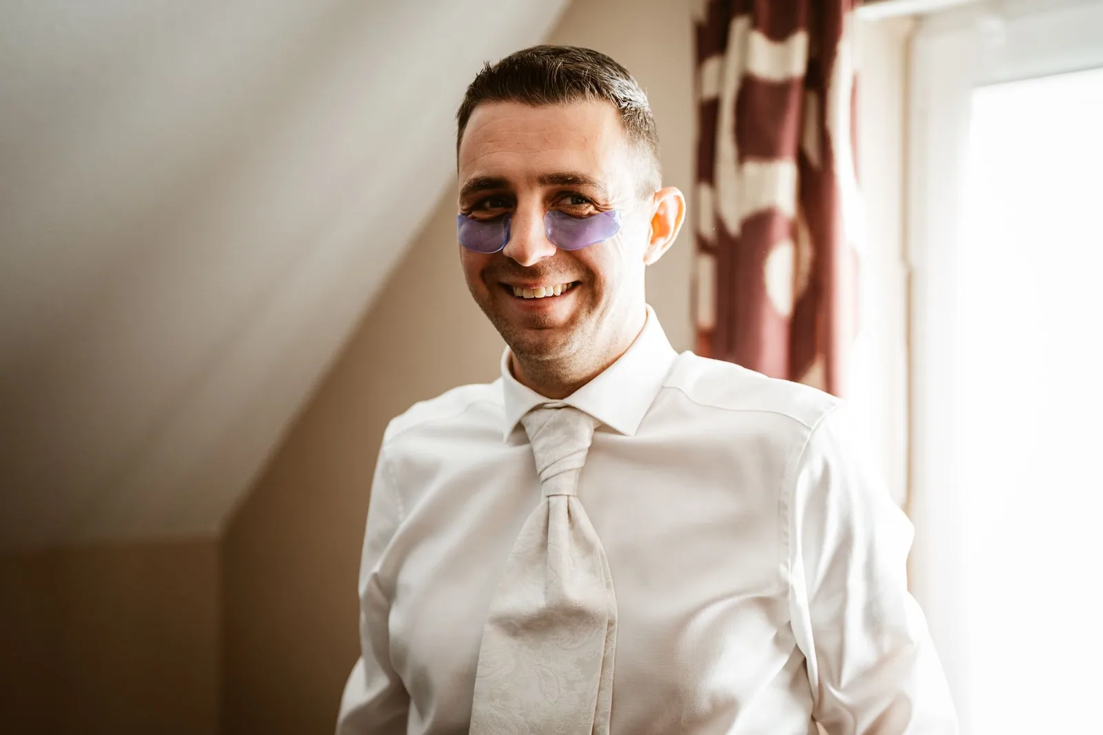 Alex lächelt beim Anziehen am Hochzeitsmorgen
